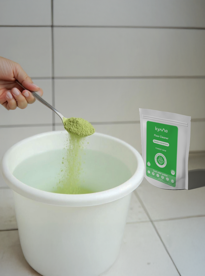 A person pouring Kyma Floor Cleaner Forest Dew powder into a bucket of water, showing the easy “just add water” preparation for an eco-friendly and refreshing home cleaning solution.