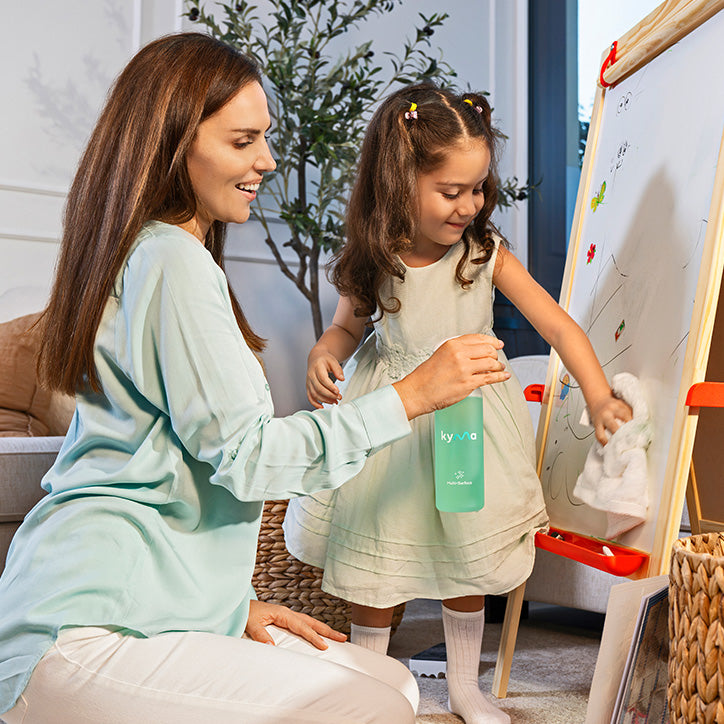 Mother and daughter cleaning an easel board together using a Kyma natural surface cleaner, promoting safe and eco-friendly home cleaning for families.