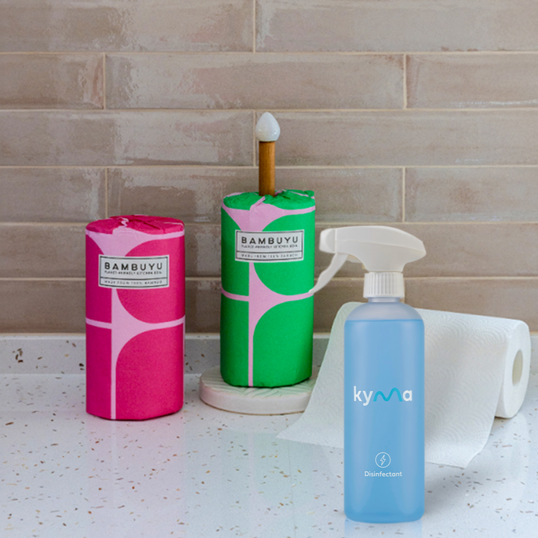 Three cleaning products from Bambuyu  X Kyma shield set on a countertop with a tiled wall background.