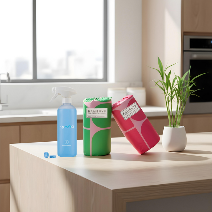 Kyma × Bambuyu The Shield Set featuring a Kyma disinfectant spray and Bambuyu reusable towels on a kitchen counter eco-friendly home cleaning bundle.